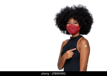 black teenager wearing protective mask against covid-19 with a smile on his face shows the vaccine brand, isolated on white background Stock Photo