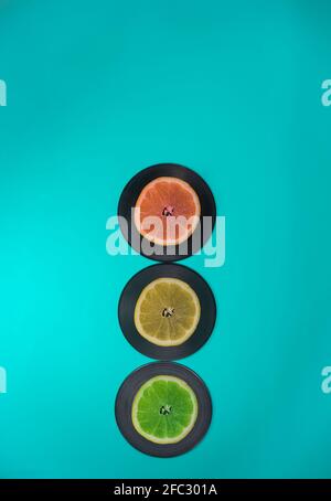 Traffic lights made of fruits and LP records. Turquoise background. Lemon, lime, grapefruit. Minimal traffic concept. Stock Photo