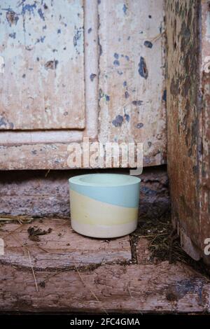 Selective focus on colorful plaster pot for cactuses in front of an old, rustic, wooden door of a house made from mud and some hay on the ground Stock Photo