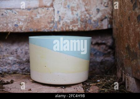 Selective focus on colorful plaster pot for cactuses in front of an old, rustic, wooden door of a house made from mud and some hay on the ground Stock Photo