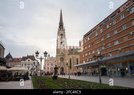 NOVI SAD, SERBIA - MARCH 11, 2017: The Name of Mary Church, or Novi Sad catholic cathedral on a cloudy afternoon with a crowd walking on Trg Slobode S Stock Photo