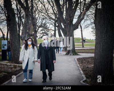 BELGRADE, SERBIA - JANUARY 1, 2021: Old senior man wearing a respiratory face mask walking in Kalemegdan park next to a middle aged woman of Belgrade, Stock Photo