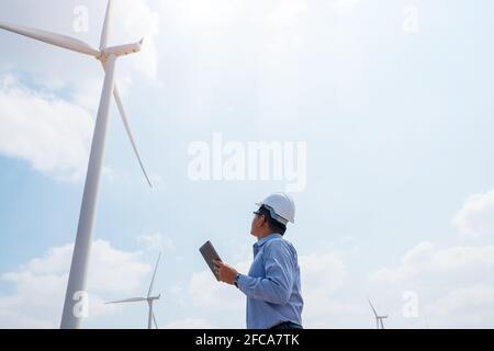 Engineer windmills working on tablet PC with the wind turbine in background Stock Photo
