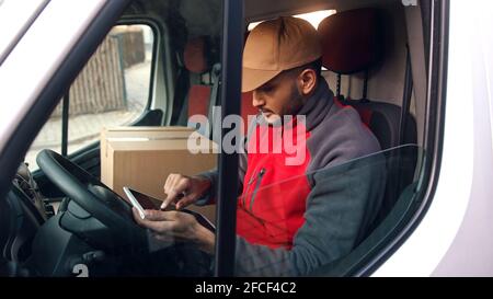 Happy indian courier using tablet in the van . High quality photo Stock Photo