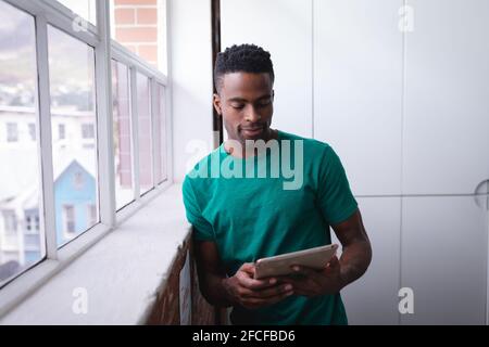 Happy african american businessman standing in office using tablet and smiling Stock Photo