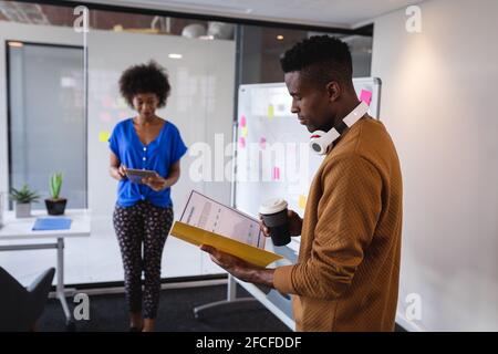 Diverse male and female colleagues standing in front of whiteboard having discussion Stock Photo