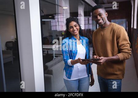 Happy diverse male and female colleagues at work discussing over tablet Stock Photo