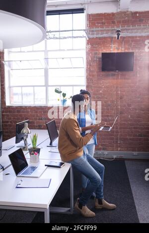 Diverse male and female colleagues at work standing discussing over laptop Stock Photo