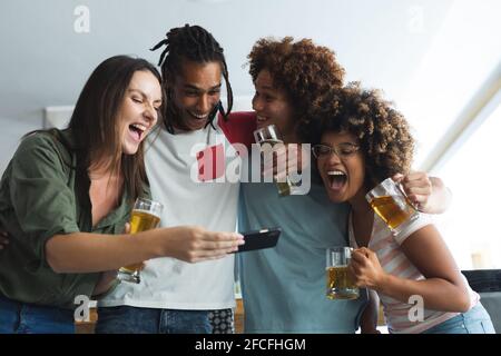 Diverse group of male and female friends looking at smartphone at bar Stock Photo