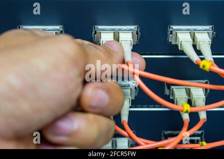 Technician connect fiber cable network to switch port in server room, Concept internet network management Stock Photo