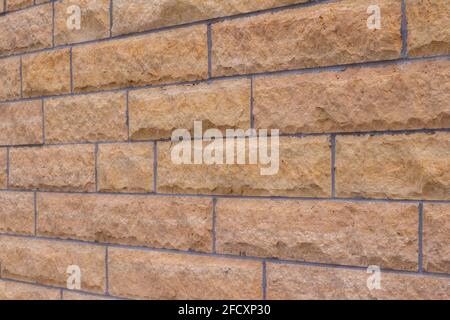 Natural rough textured stone block wall background in shades of beige, with large stone bricks of varying widths Stock Photo