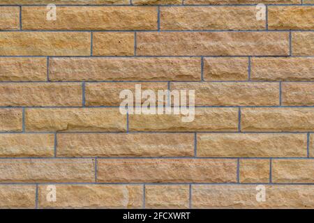 Natural rough textured stone block wall background in shades of beige, with large stone bricks of varying widths Stock Photo