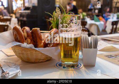 Close up Appetizing German Recipe with Sausage. Classic German dinner of fried sausages with braised cabbage on large white plates with light beer, st Stock Photo