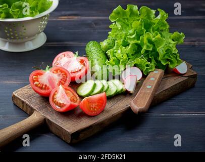 various fresh sliced vegetables on wooden cutting board Stock Photo