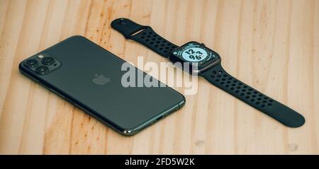 Apple iPhone 11 pro max and apple watch series 6 lay flat on a wooden table, luxury and lifestyle concept. Stock Photo