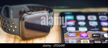 Apple I watch series 6 and iPhone 11 pro max lay flat on a wooden table, touchscreen luxury smartwatch in sync Stock Photo