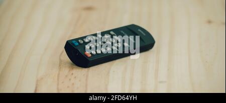 Small Remote controller lay flat on a wooden surface close up photograph. Stock Photo