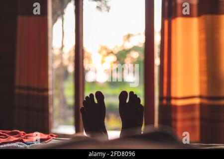 Relaxing feet and the beautiful view from the inside cabana door. Enjoying the vacation in a rural village while taking a nap in a comfy bed. Stock Photo