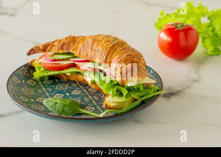 Crispy croissant with salmon, lettuce and cucumbers. Tasty breakfast. Stock Photo