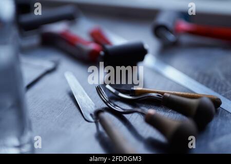 Lithographic tools in dark colors with wooden handles on a table. Linocut concept. Cutting instruments for linocut making. High quality photo Stock Photo