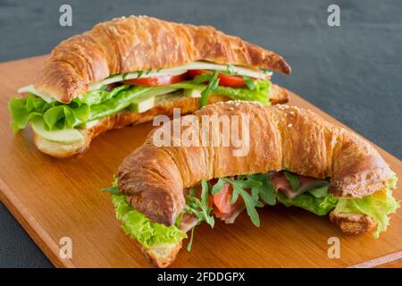 Crispy croissant with salmon, lettuce and cucumbers. Tasty breakfast. Stock Photo