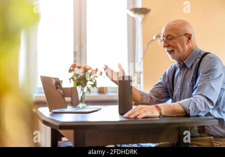 Senior man using Virtual Assistant at home Stock Photo