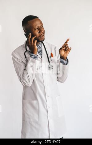 Closeup picture of young African American doctor standing in white uniform against white background Stock Photo
