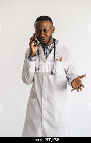 An African-American black young doctor in a white coat is talking on the phone. isolated  Stock Photo