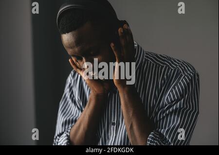 Young african man listening to music with wireless earphones and dancing at home Stock Photo