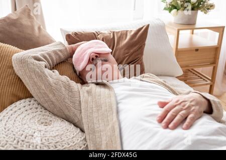 Sleeping senior man in sleep eye mask on bed at home Stock Photo