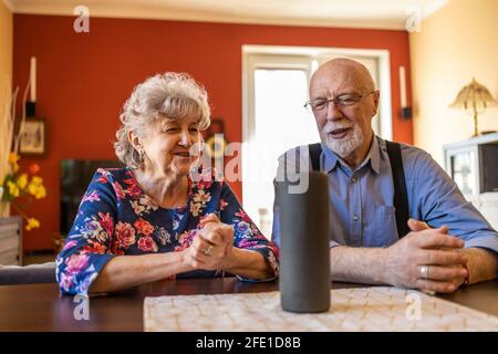 Excited senior couple using a Virtual Assistant at home Stock Photo