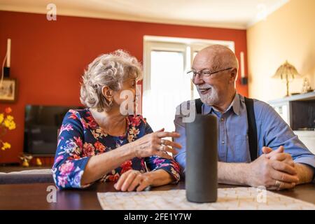 Excited senior couple using a Virtual Assistant at home Stock Photo