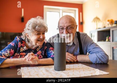 Excited senior couple using a Virtual Assistant at home Stock Photo