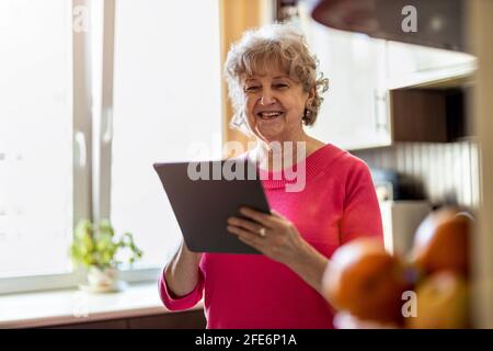 Happy senior woman using digital tablet at home Stock Photo