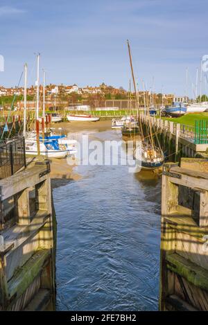 Looking through the lock gates at Rye harbour on the estuary of the river Rother, with the village of Rye in the background. Stock Photo