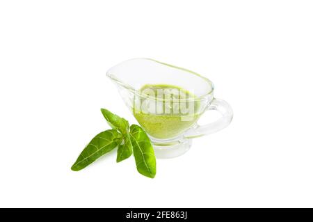 Delicious, fresh pesto sauce made with basil, olive oil, garlic and pine nuts. Green pesto sauce in a gravy boat on a white background. Stock Photo