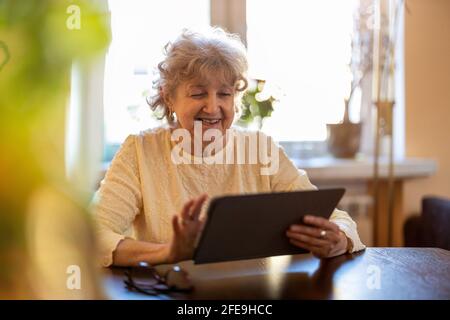 Happy senior woman using digital tablet at home Stock Photo