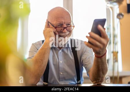 Shot of a senior man using a mobile phone at home Stock Photo