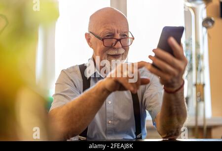 Shot of a senior man using a mobile phone at home Stock Photo
