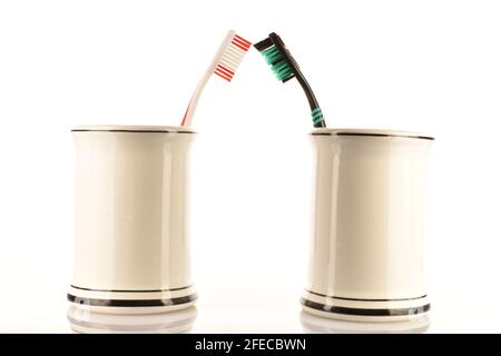 Two toothbrushes in a light ceramic glass on a white background. Stock Photo