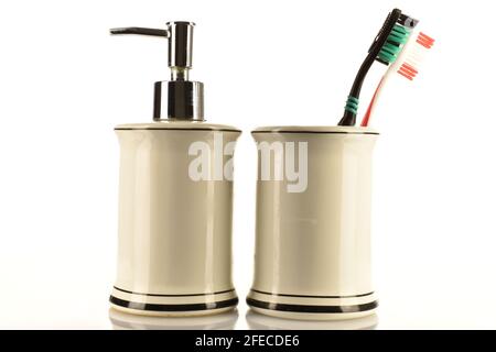 Two toothbrushes in a light ceramic glass and a ceramic container for soap on a white background. Stock Photo