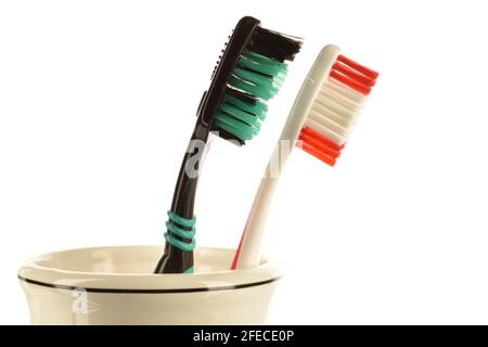 Two toothbrushes in a light ceramic glass on a white background. Stock Photo
