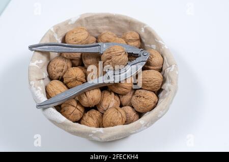 basket with whole walnuts and nutcracker on a white background, top view Stock Photo