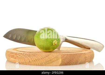 One ripe lime with a knife on a bamboo tray, on a white background. Stock Photo