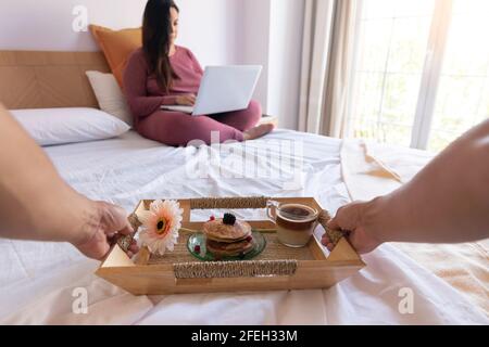 Man bringing his partner breakfast in bed. Selective focus on the pancakes Stock Photo