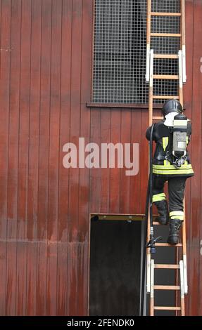 Fire fighters firemen on long ladders in action to fight a spectacular ...