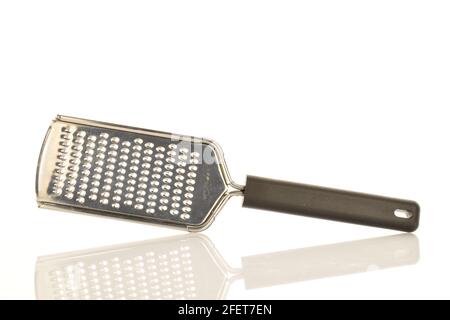 One metal grater with a black plastic handle, for the kitchen, close-up, isolated on white. Stock Photo