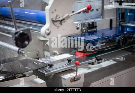 Automatic food package flow wrapping machine. Food packaging machine in food industry. Stock Photo