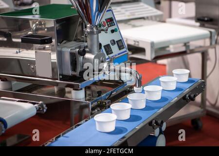 Cream filling machine in bakery processing. Food depositor machine. Food industry Stock Photo