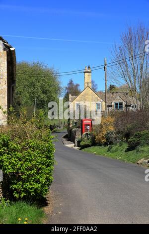 The pretty village houses of Compton Abdale in The Cotswolds with a vintage traditional red telephone box Stock Photo